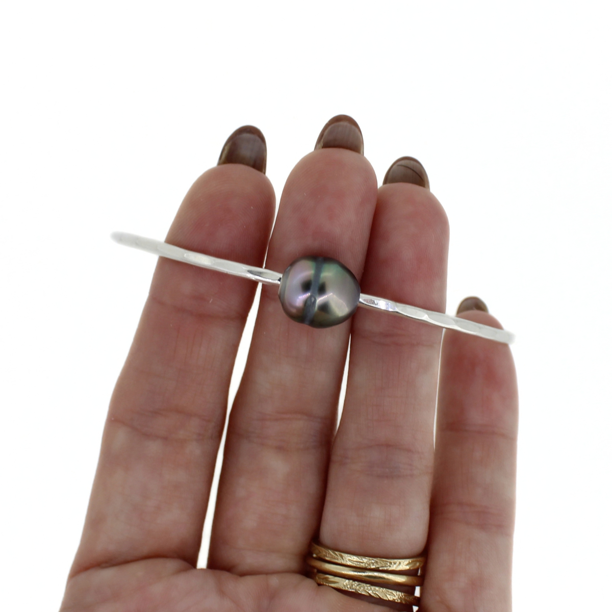 Silver Tahitian pearl bangle bracelet shown on a persons fingers for size reference 