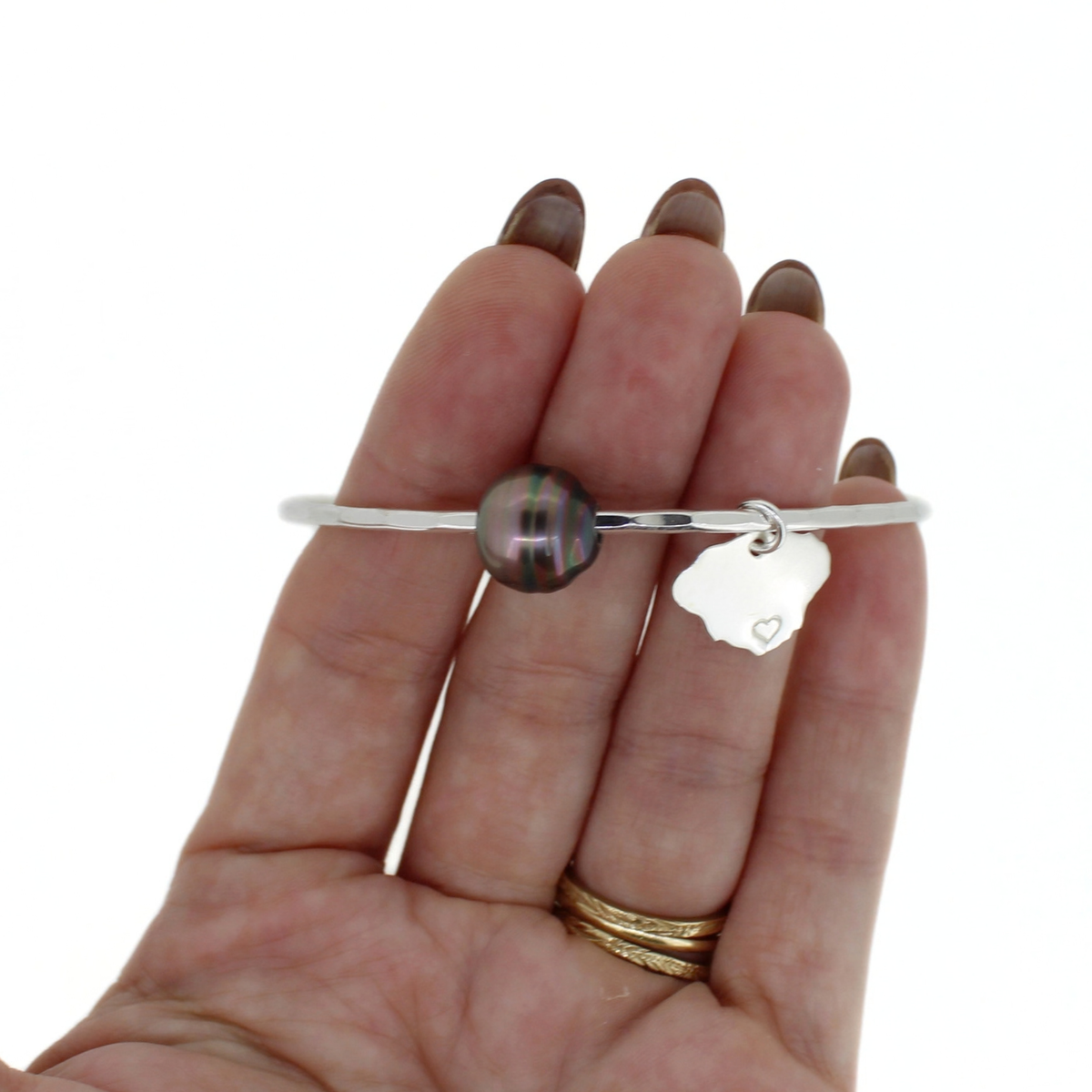 Silver Tahitian pearl bangle with Kauai island charm shown on a persons hand for size reference 