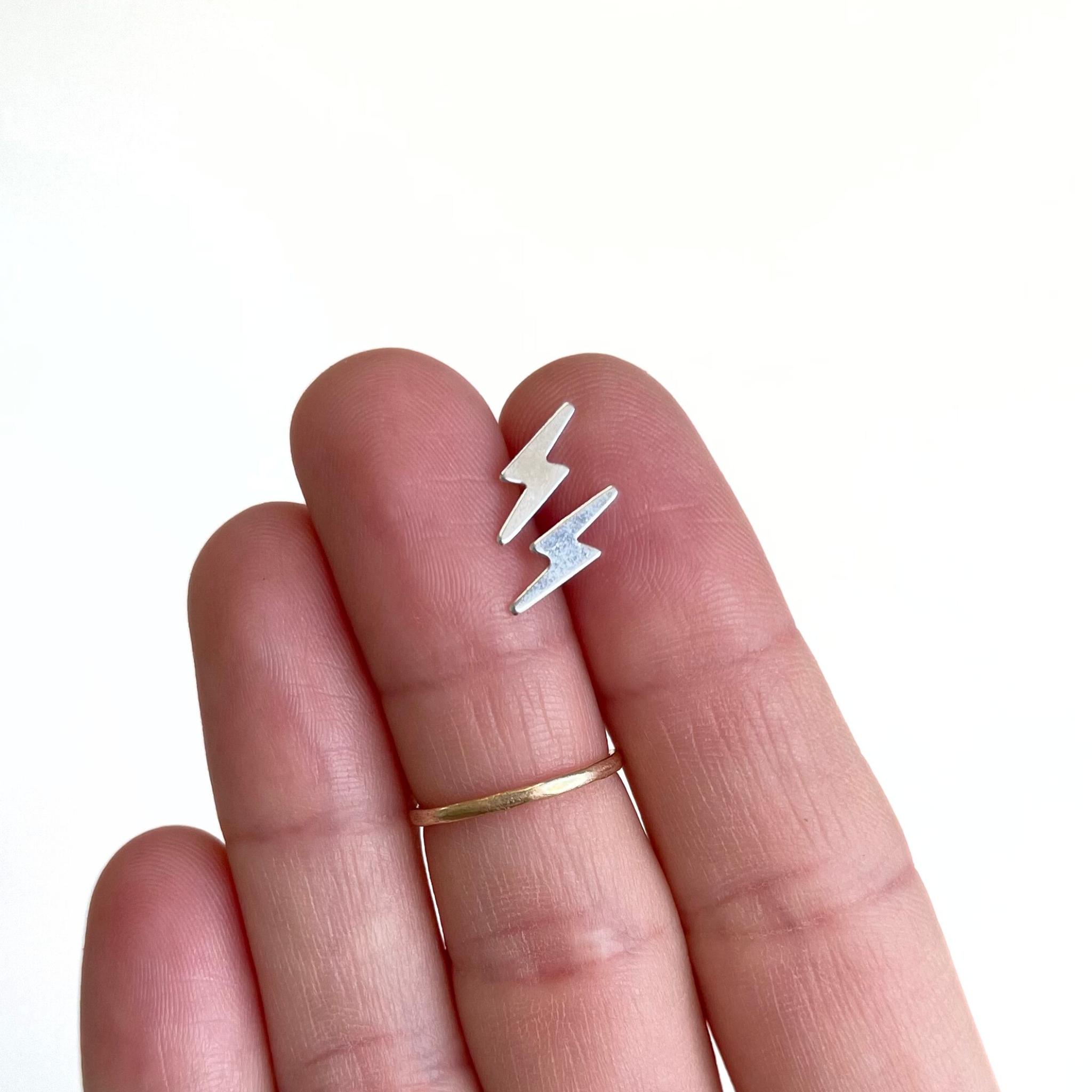 Brianne & Co. sterling silver small lightning bolt stud earrings in hand for size reference