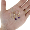 Brianne & Co. gold fill 18mm hoop earrings with amethyst gemstones on hand for size reference 