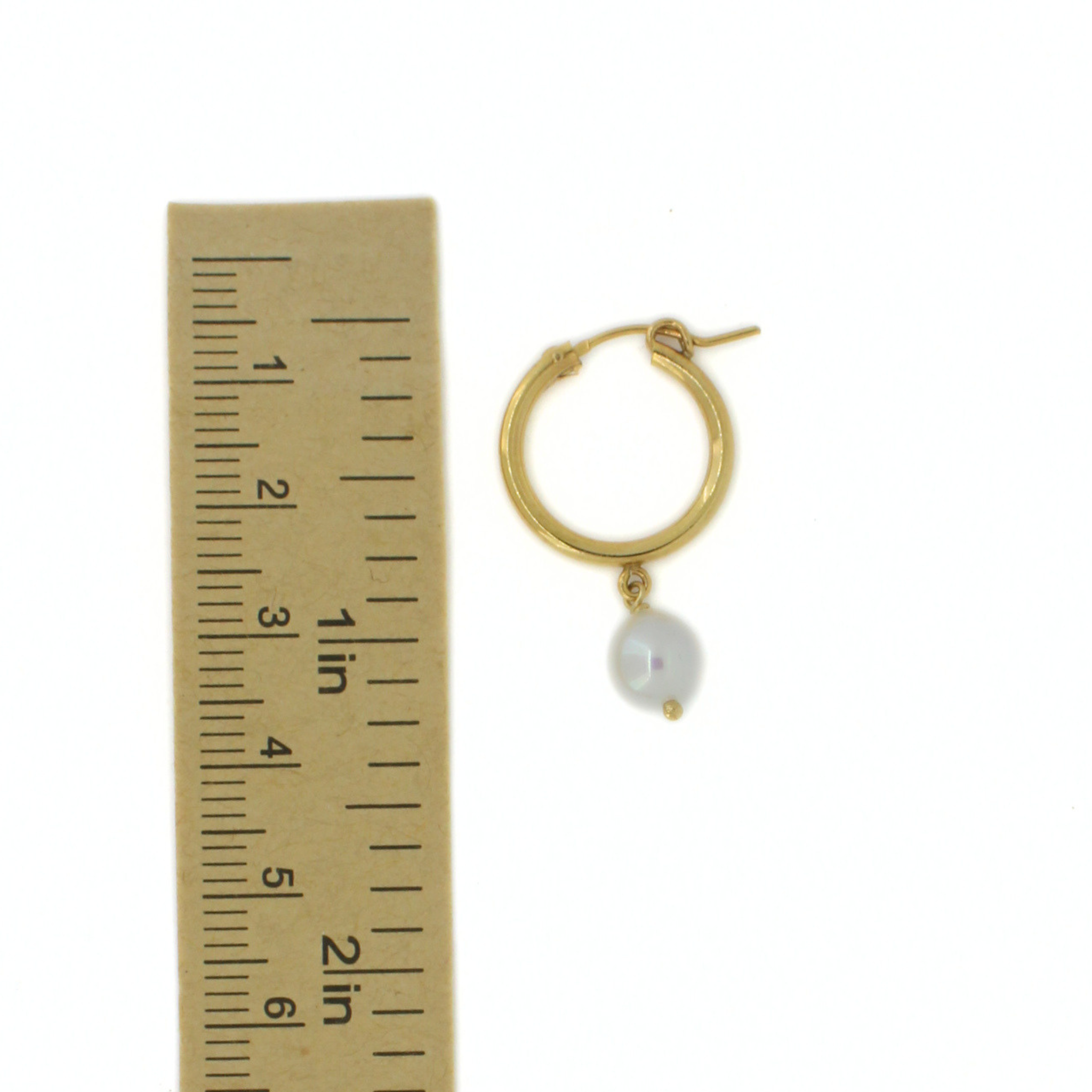 A single gold hoop earring with a dangling white pearl, shown next to a ruler for scale on a white background.