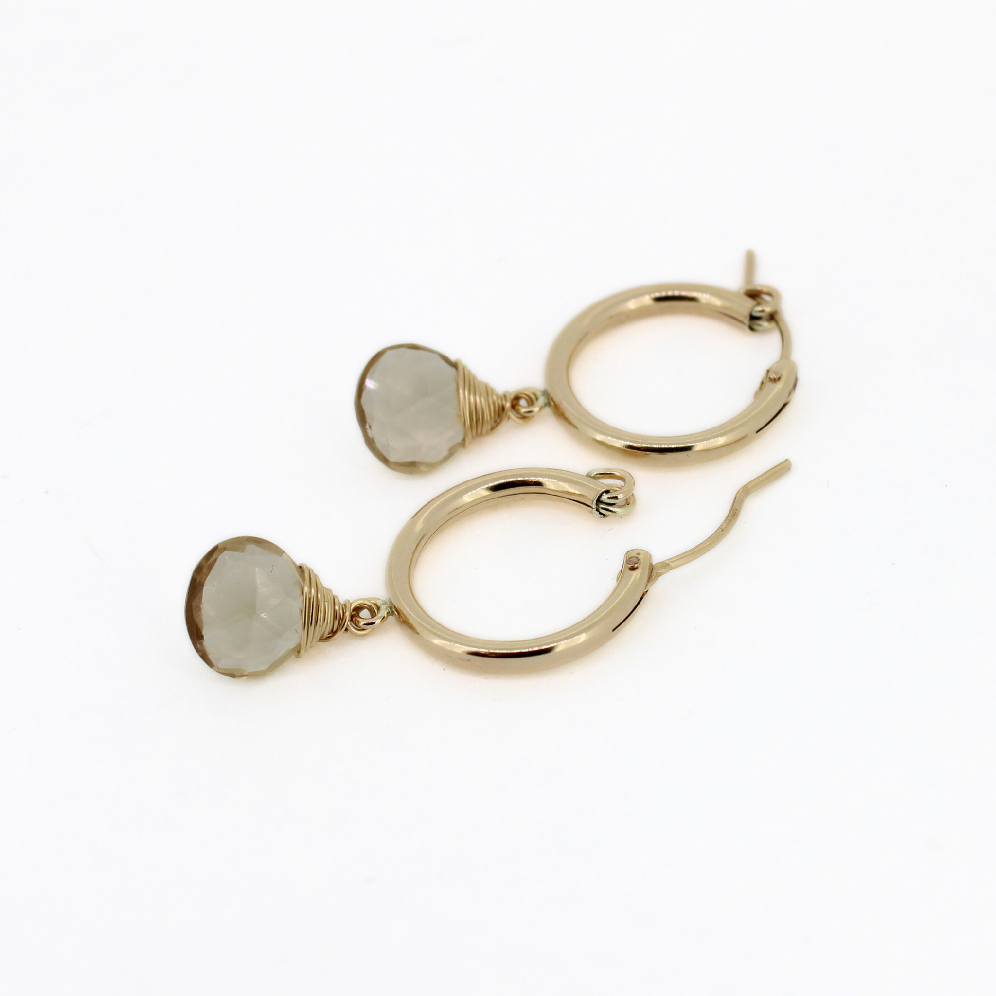 Gold hoop earrings with champagne topaz dangle charms, laid out flat