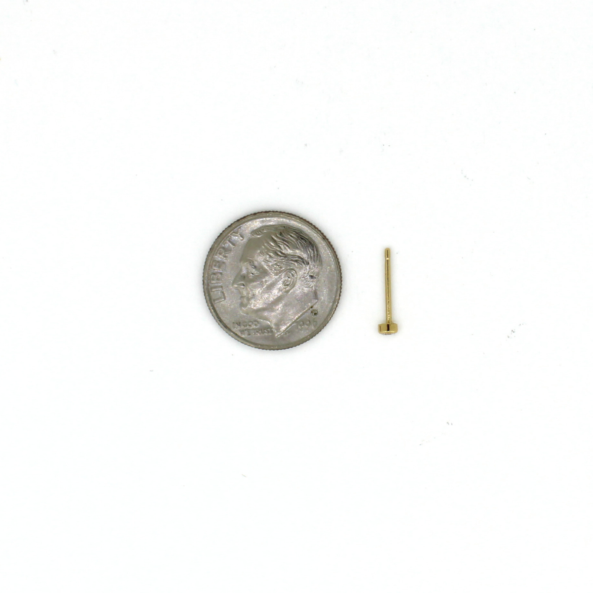 Tiny gold stud earring next to a US dime for size reference