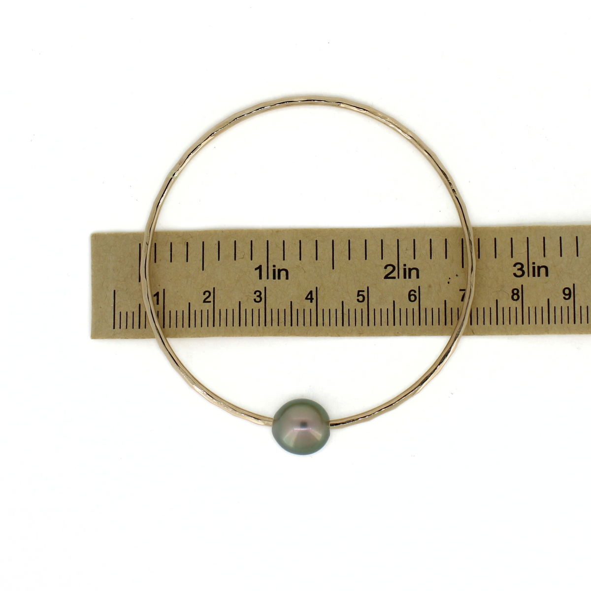 Gold Tahitian pearl bangle bracelet shown over a ruler for size reference 