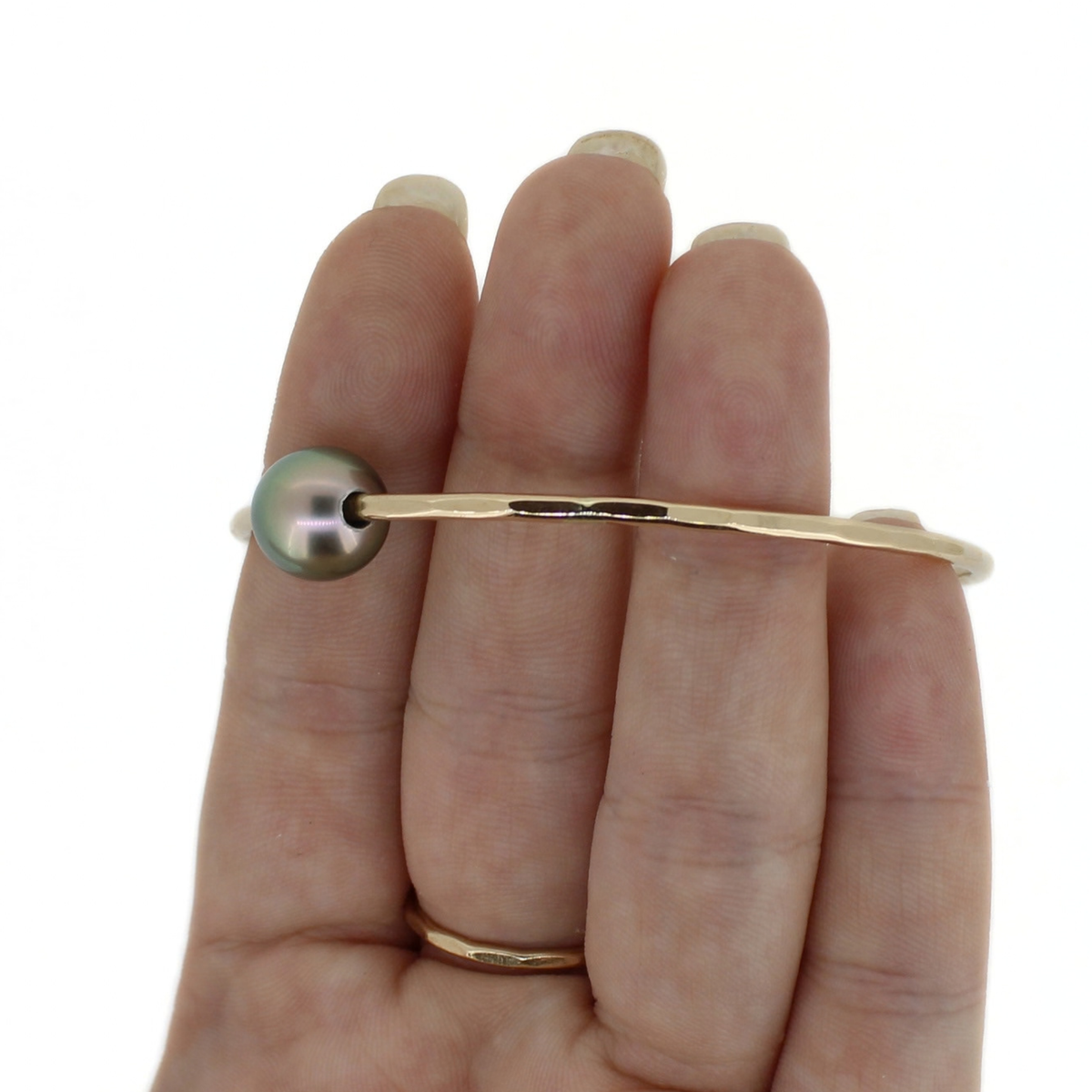 Gold bangle bracelet unclose of the hammered texture, shown on a persons hand