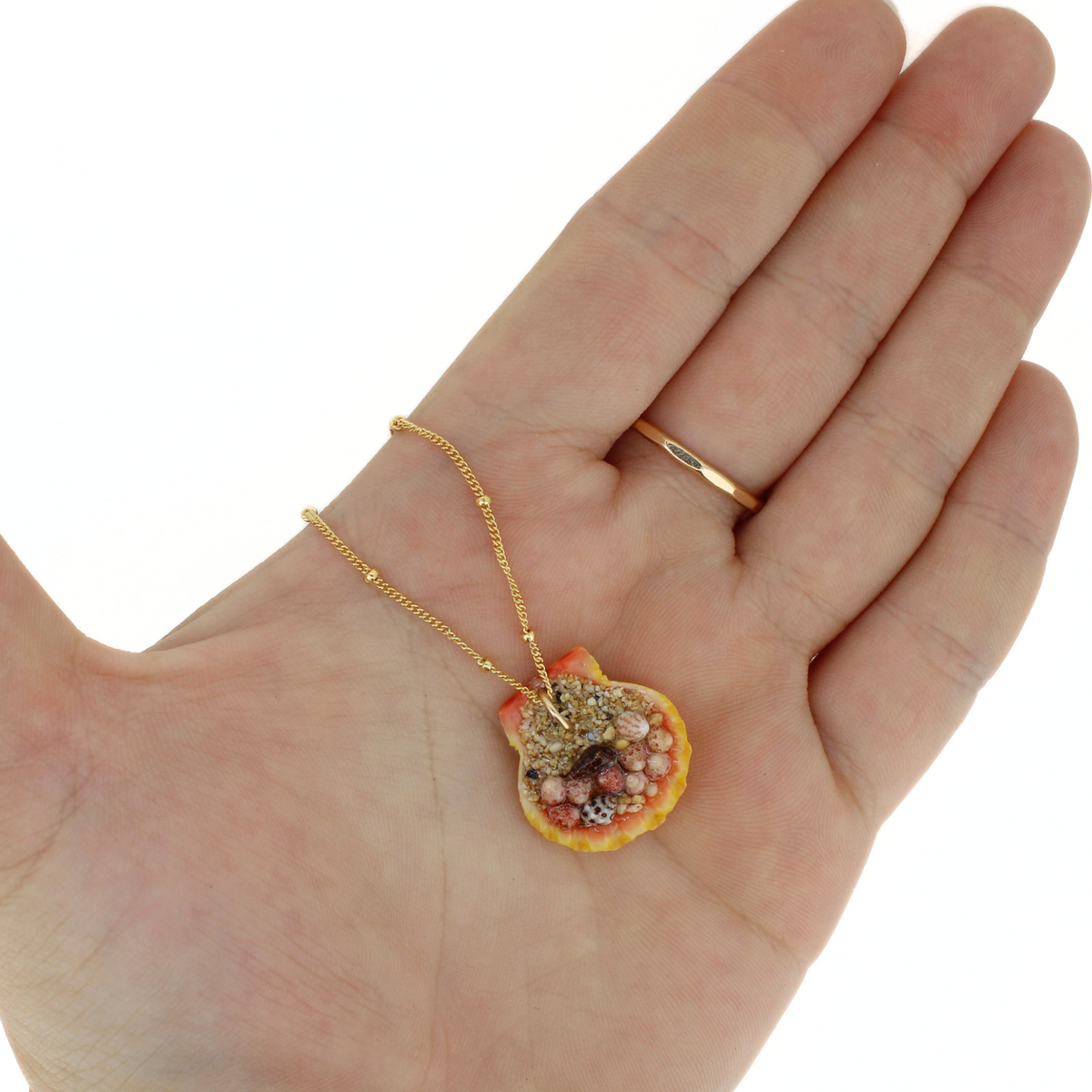 Back side of a sunrise shell pendant showing sand and tiny shells securing the pendant bail