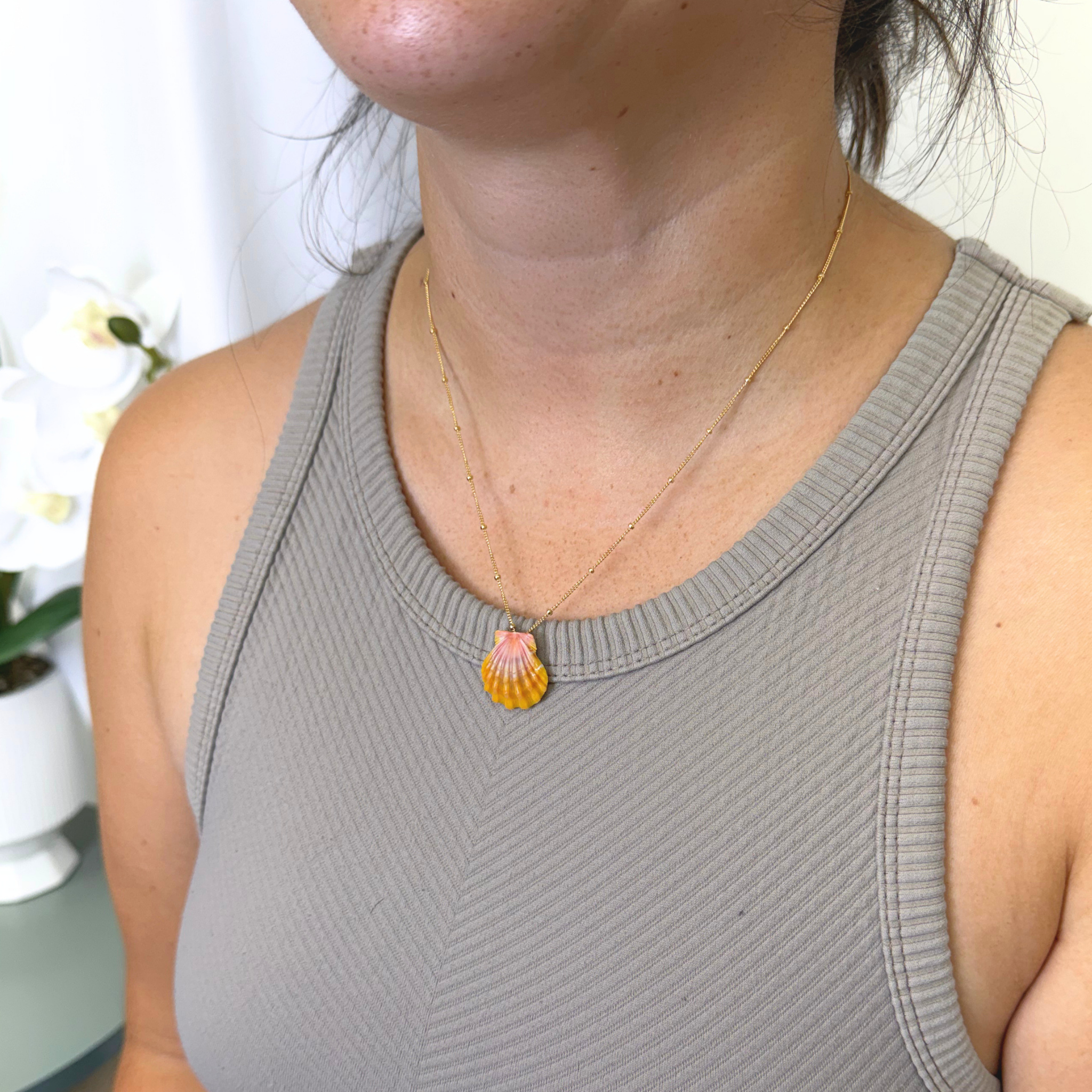 Woman wearing a Hawaiian sunrise shell pendant on a gold chain