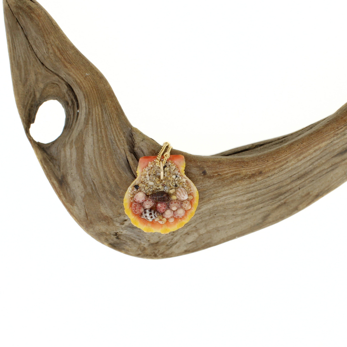 Back side of a sunrise shell pendant showing sand and tiny shells securing the pendant bail