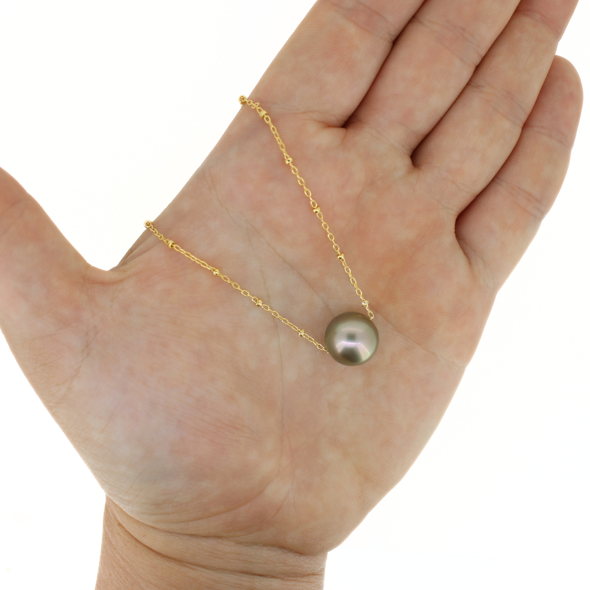 Gold floating Tahitian pearl necklace shown on a hand for size reference. 