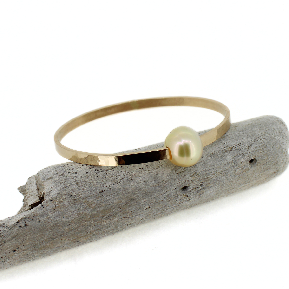 Brianne & Co. 14k gold fill extra thick bangle bracelet featuring a large golden south sea pearl displayed on drift wood