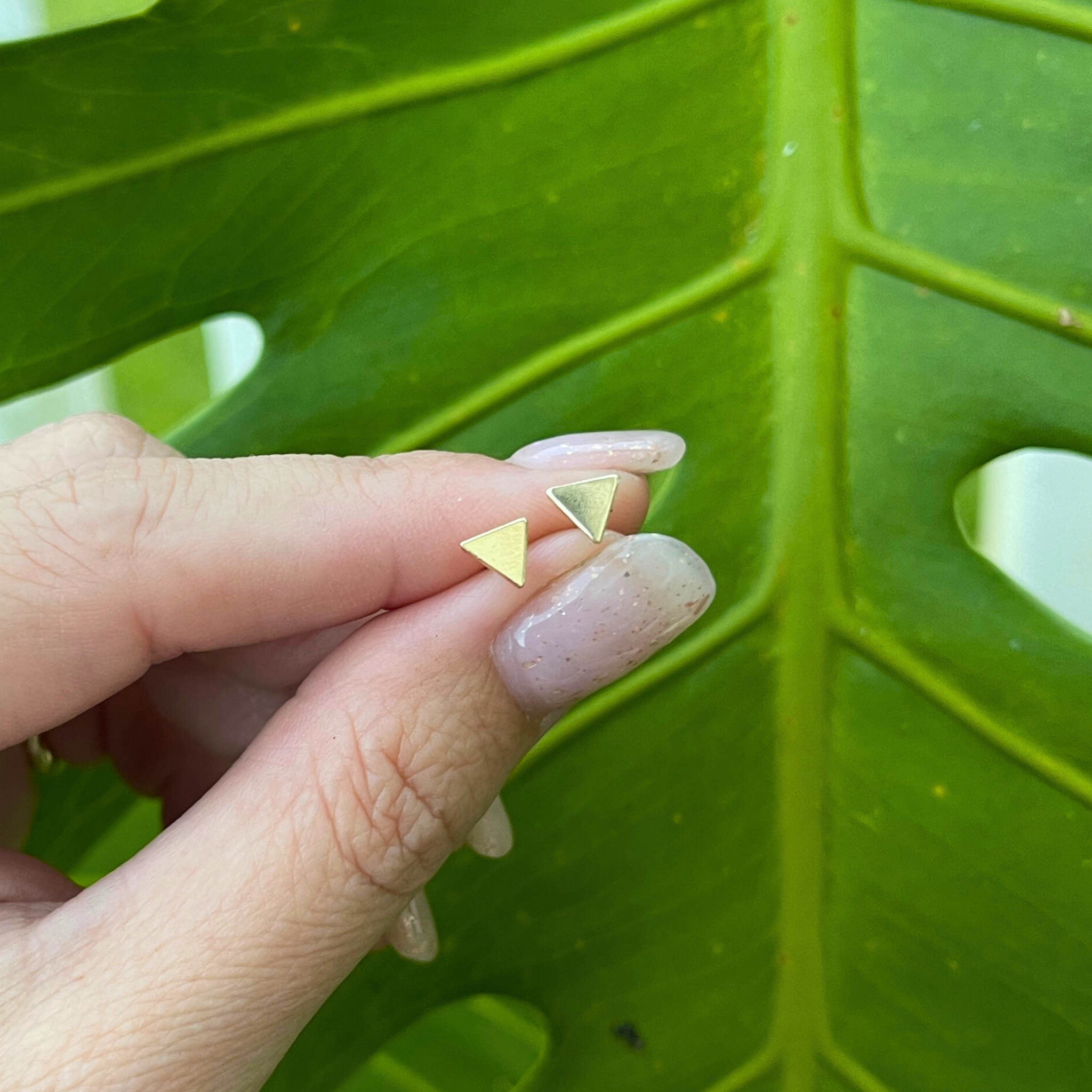 Brianne & Co. 14k gold filled tiny triangle stud earrings in hand for size reference 