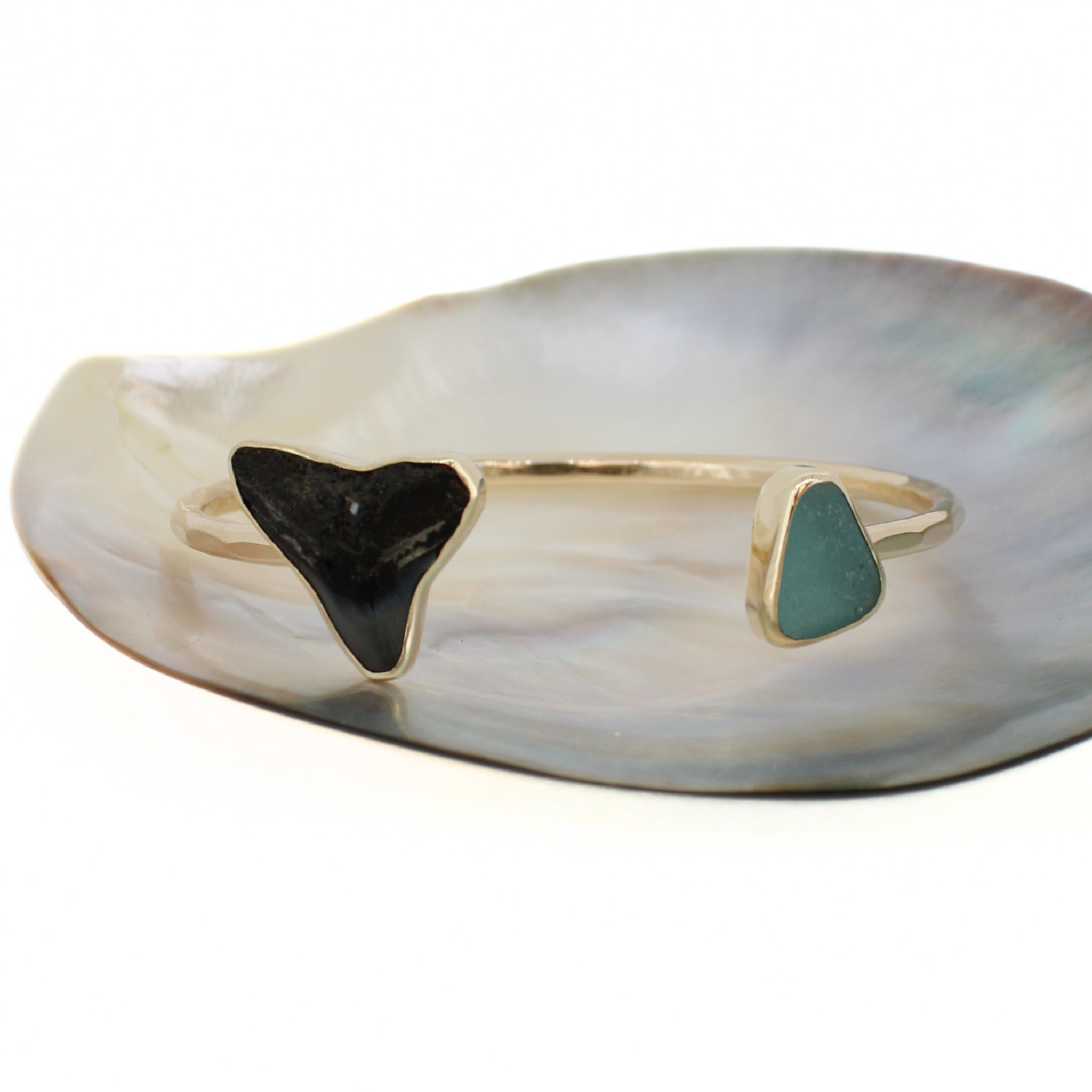 Gold cuff bracelet with black shark tooth and green sea-glass triangle inlays