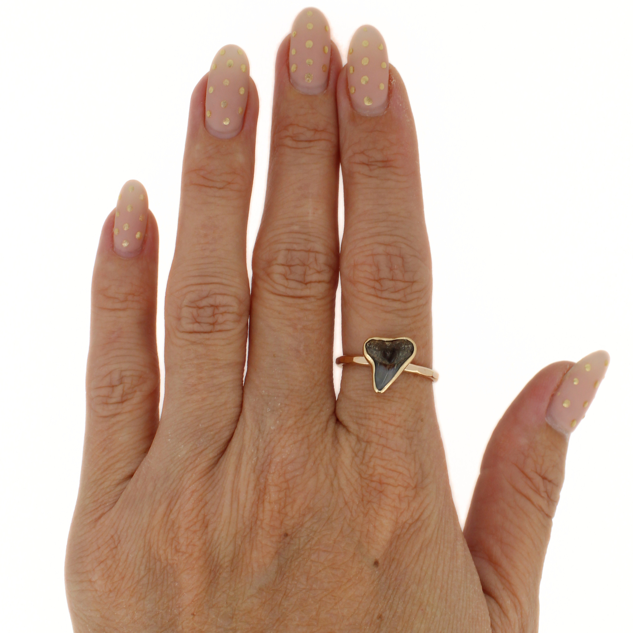Gold shark tooth ring on finger, dark triangle tooth setting