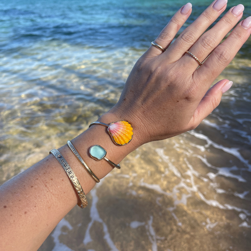 Brianne & Co. gold sunrise shell and sea glass bypass style cuff on wrist