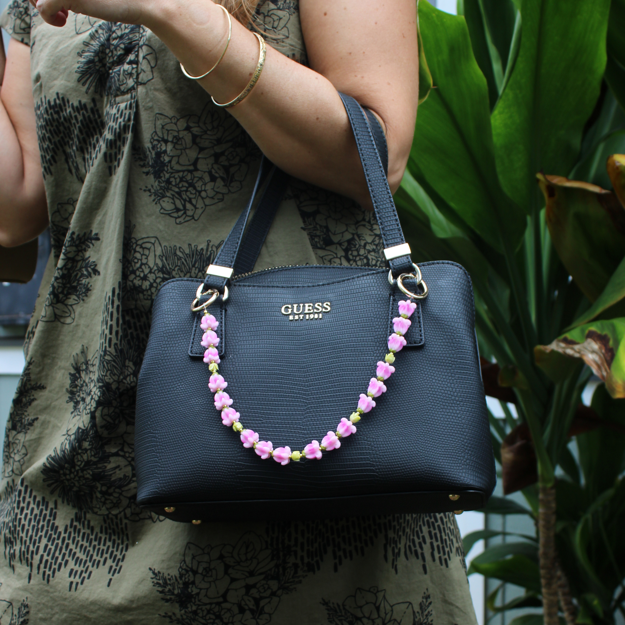 Brianne & Co. short purse lei feating pink crown flowers, green pakalana flowers and gold accents handmade on Kauai