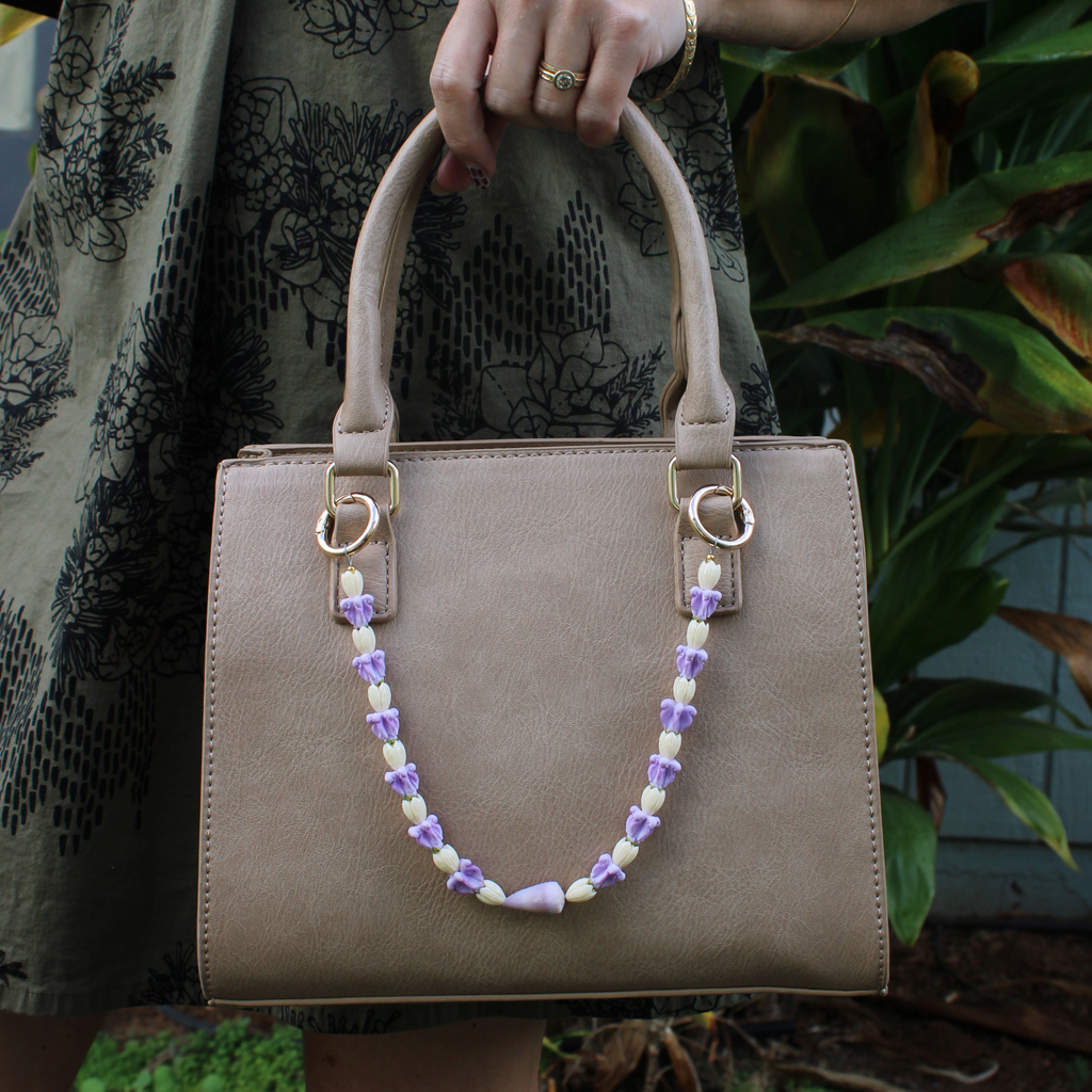 Brianne & Co. purse lei featuring pikake and crown flowers and a little purple cone shell from Kauai
