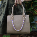 Brianne & Co. purse lei featuring pikake and crown flowers and a little purple cone shell from Kauai