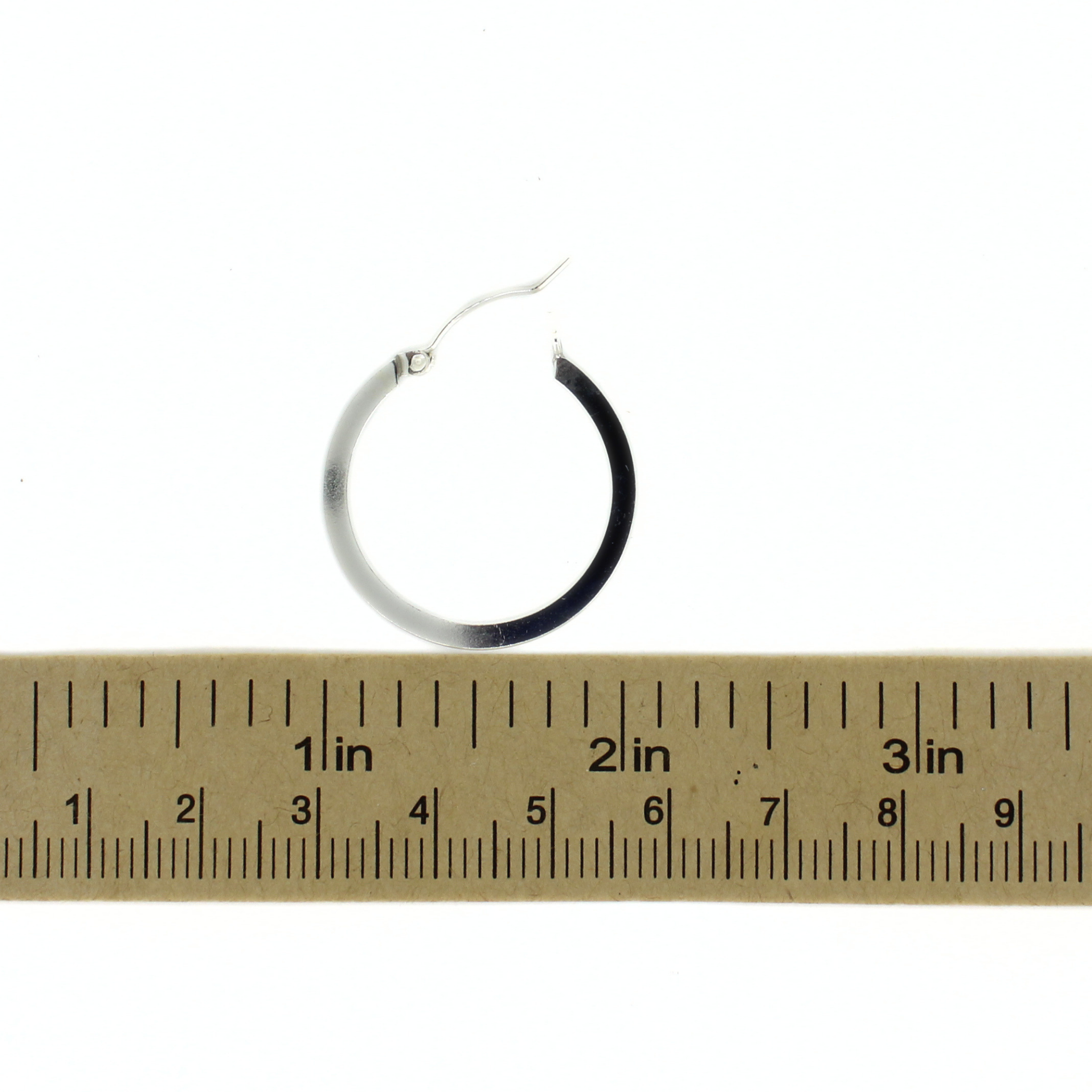 Sterling silver hoop earrings next to a ruler for size reference