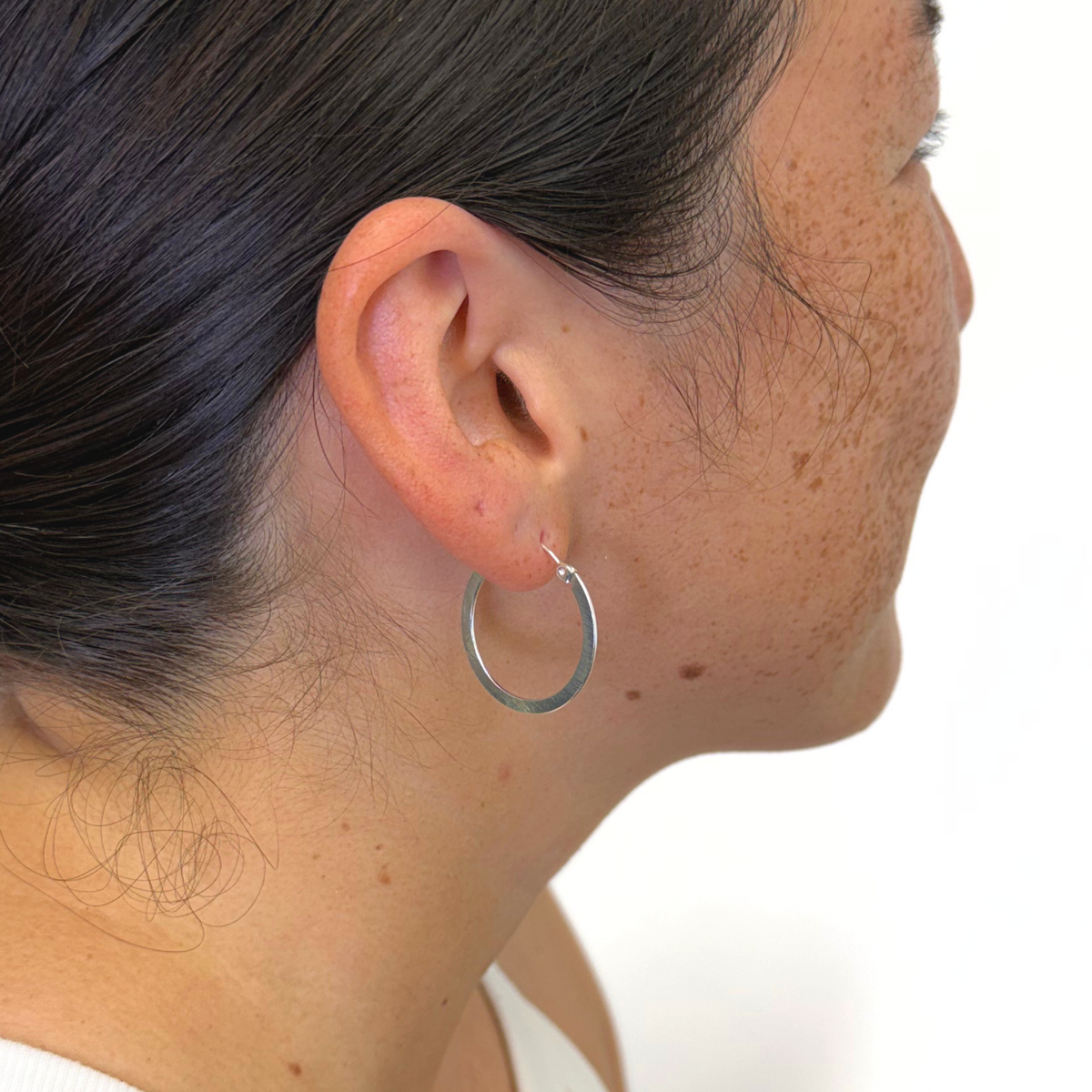 Sterling silver polished hoop earrings on a woman's ear