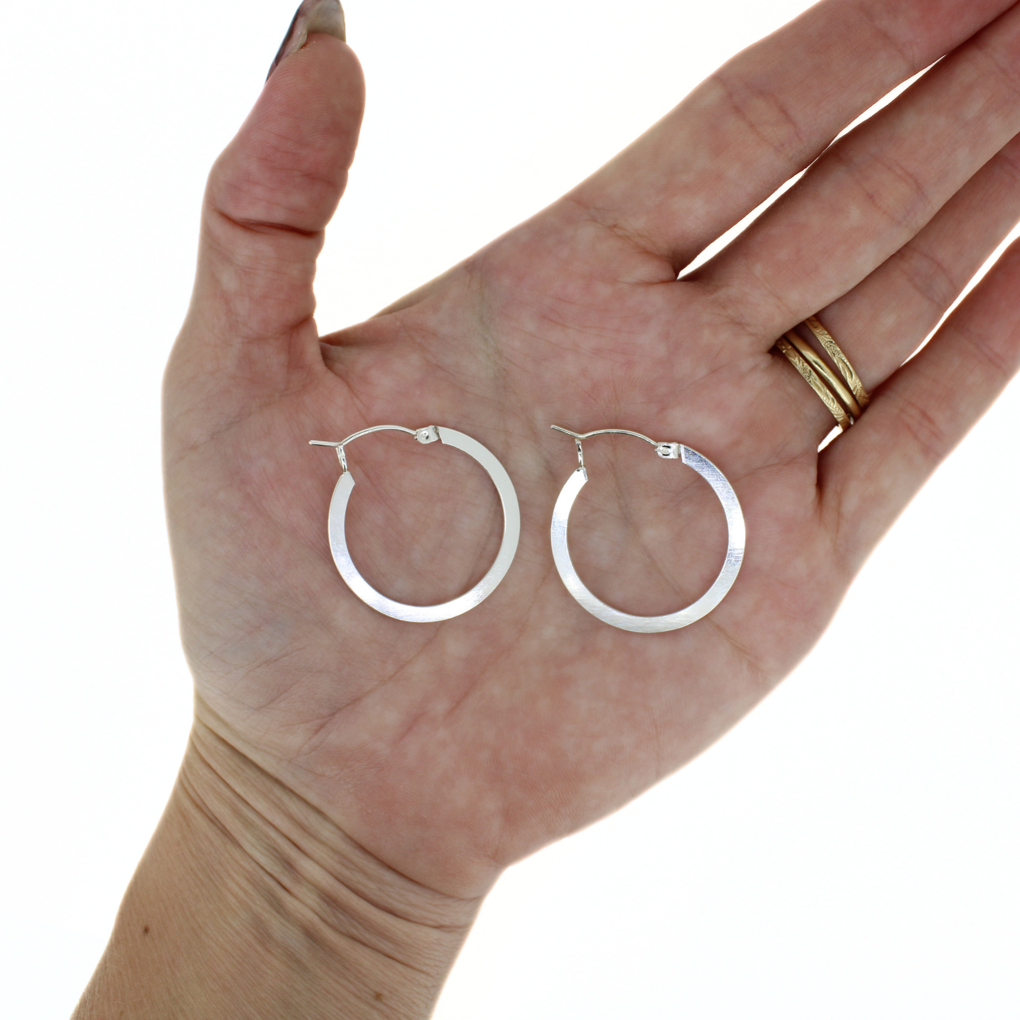 Brianne & Co. sterling silver flat hoop earrings on a hand against a white background 