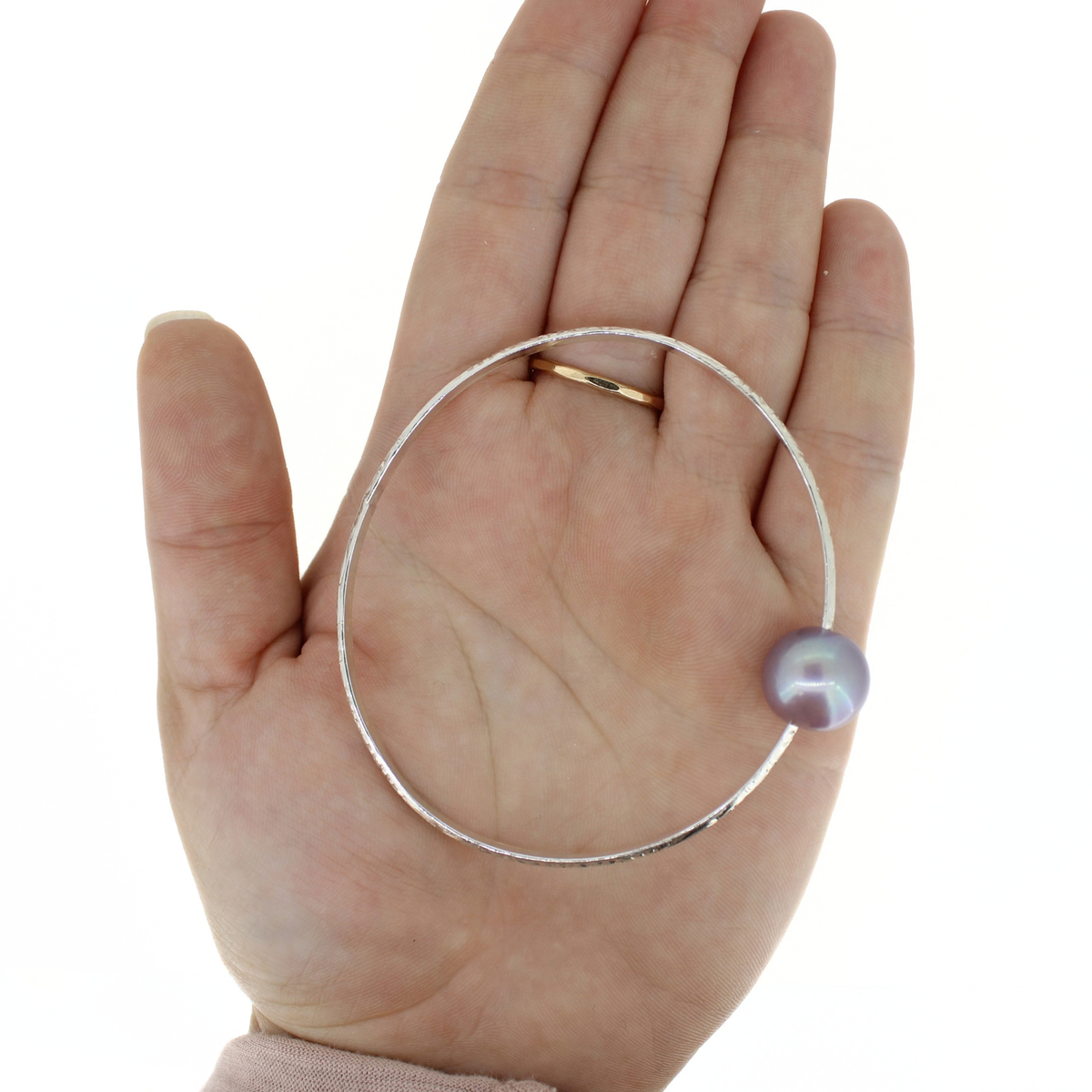 Sterling silver Edison pearl bangle bracelet displayed on an open palm for size reference 