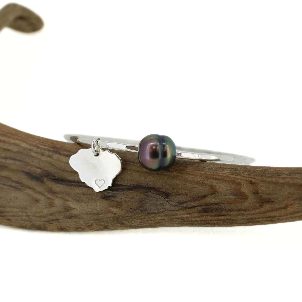 Sterling silver Tahitian pearl Kauai charm bangle bracelet displayed on driftwood