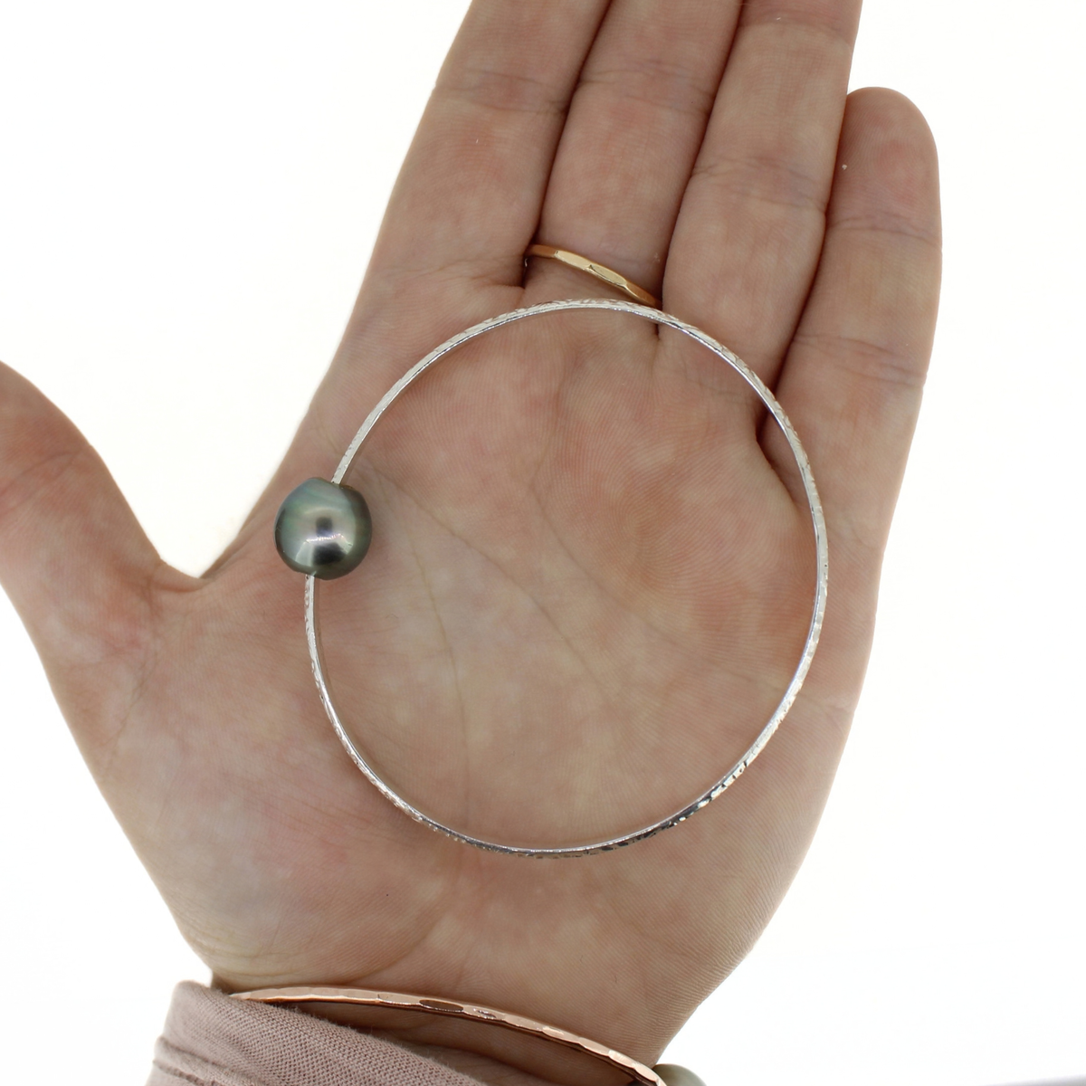 Sterling silver heirloom style bangle bracelet with Tahitian pearl displayed on an open palm