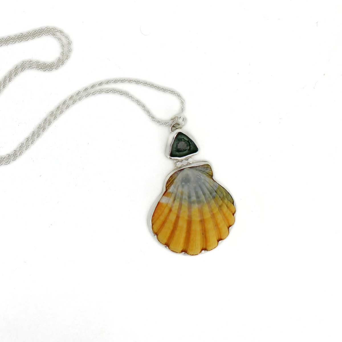 A silver chain necklace featuring a scallop shell pendant with a dark blue tourmaline stone set above it, displayed on a clean white background.