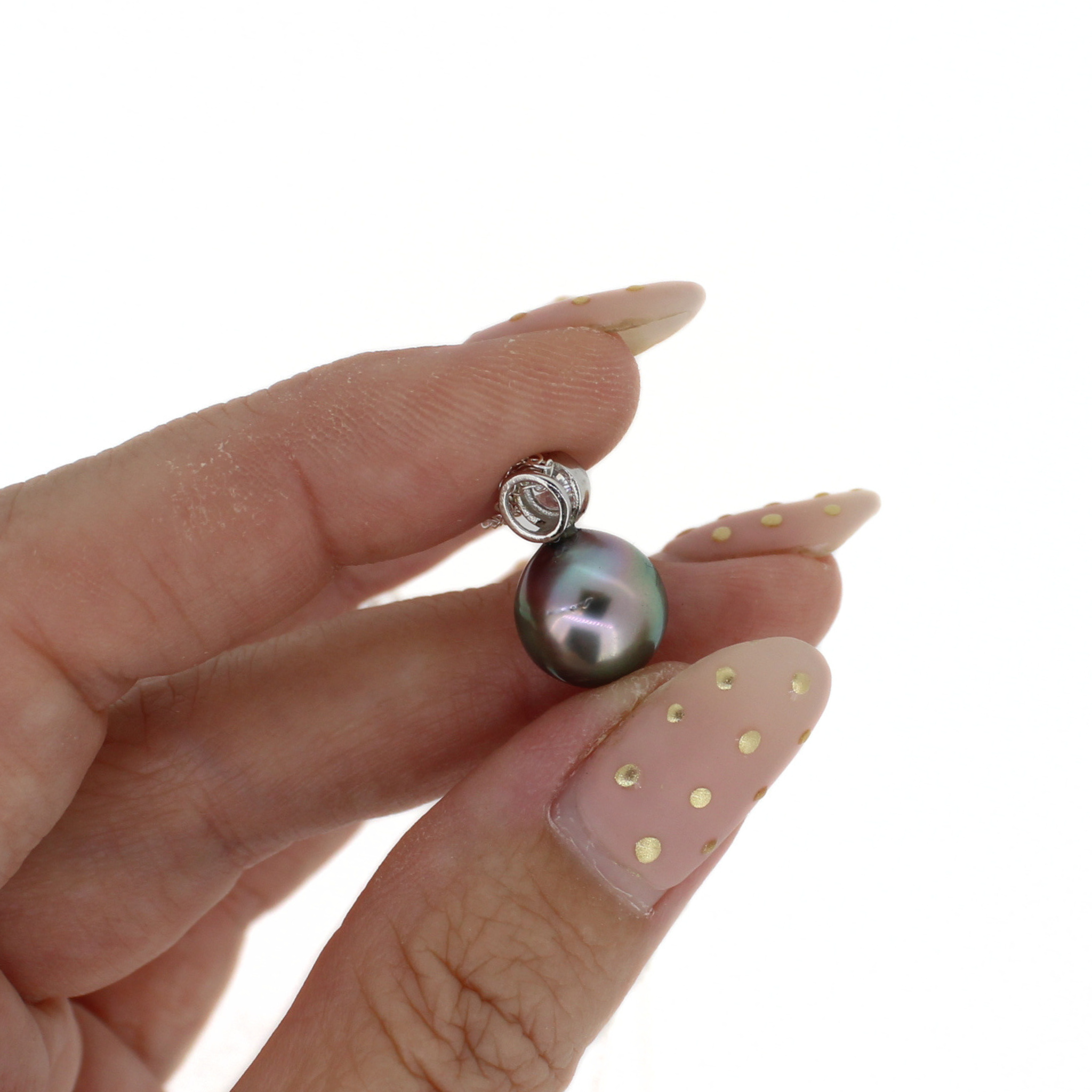 A close-up of a hand holding a single round dark gray pearl pendant with a silver bezel setting against a plain white background.