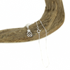 Silver pineapple charm necklace on a piece of driftwood with a white background