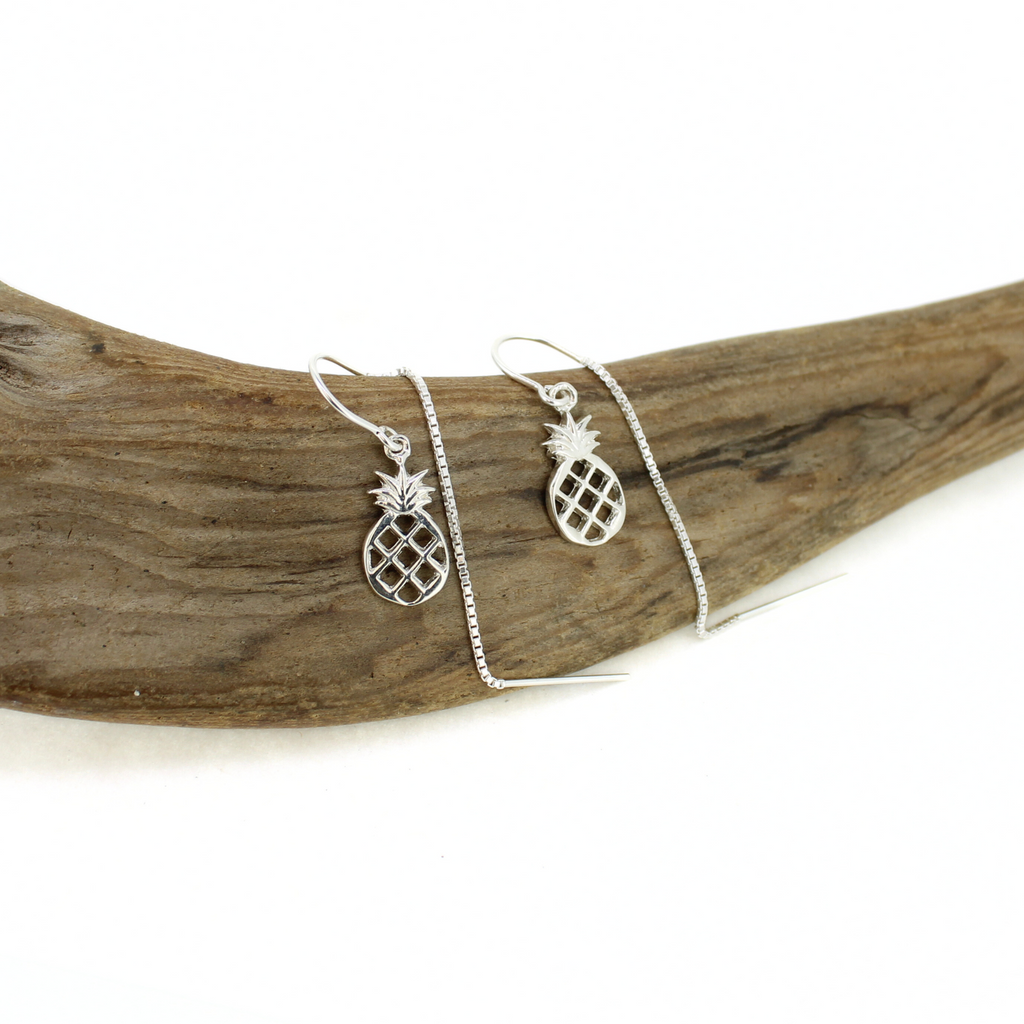 Silver pineapple threader earrings on a piece of driftwood