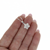 Brianne & Co. small sterling silver CZ plumeria necklace on finger for size reference 