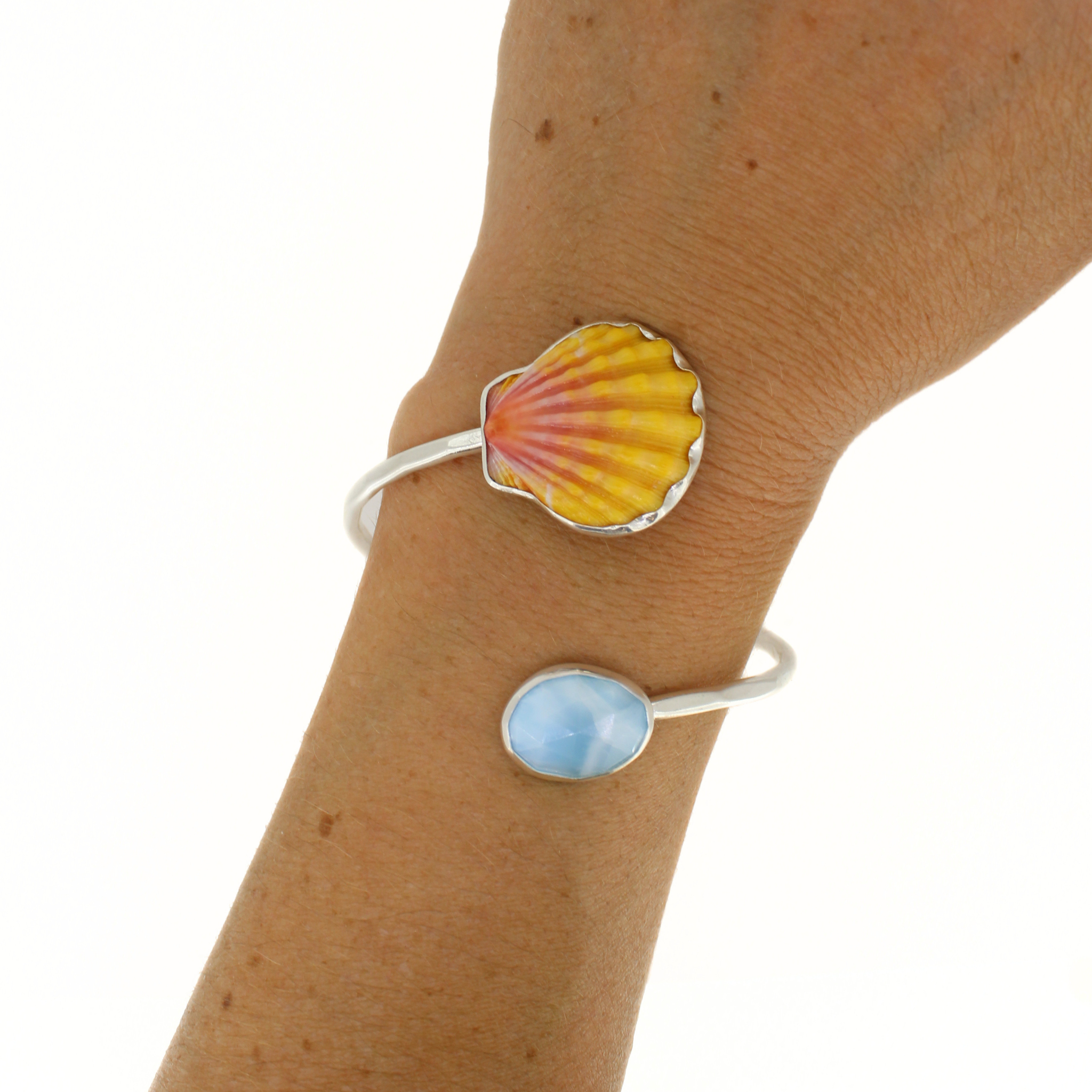 Sterling silver bypass cuff with scalloped yellow orange shell face and blue oval stone