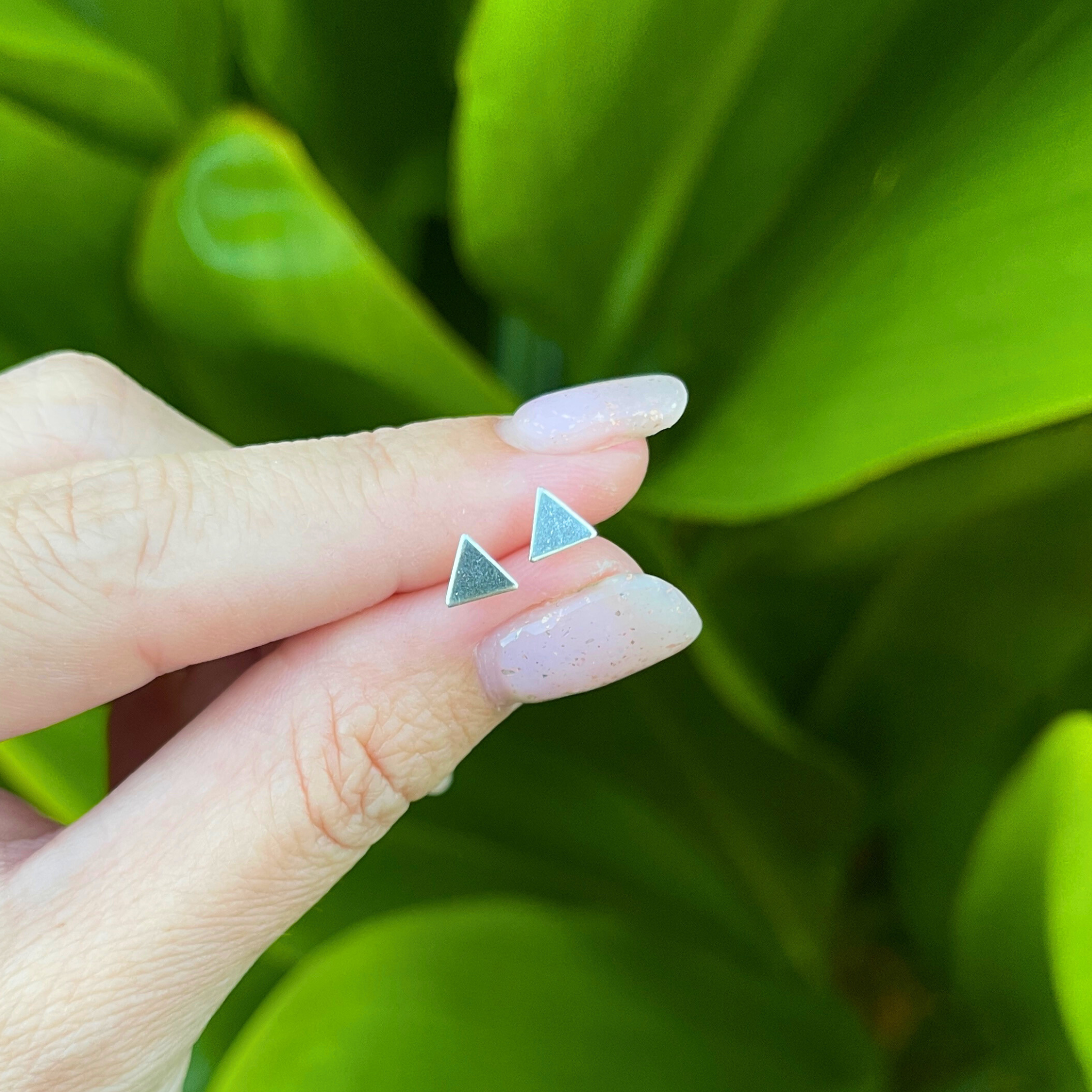 Brianne & Co. sterling silver tiny triangle studs in hand for size reference