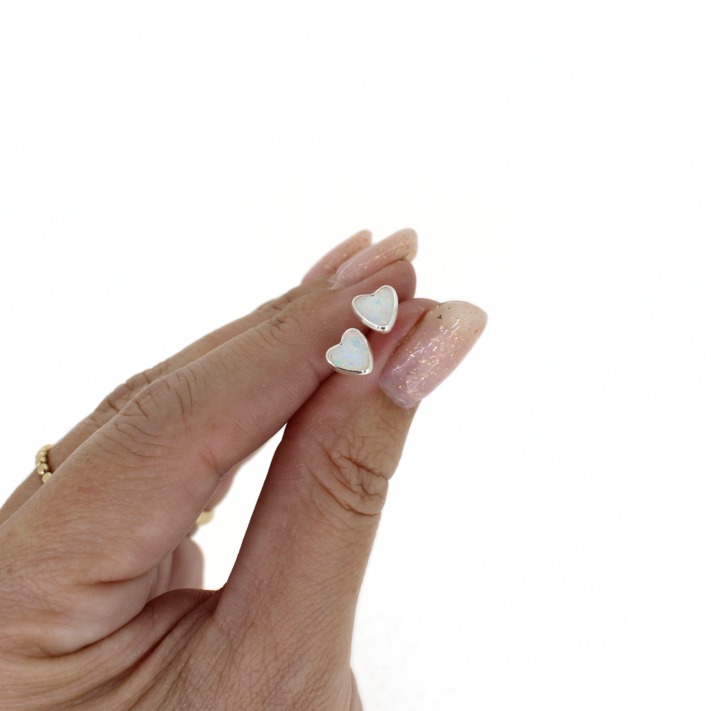 Brianne & Co. sterling silver heart shaped simulated opal stud earrings in hand for size reference