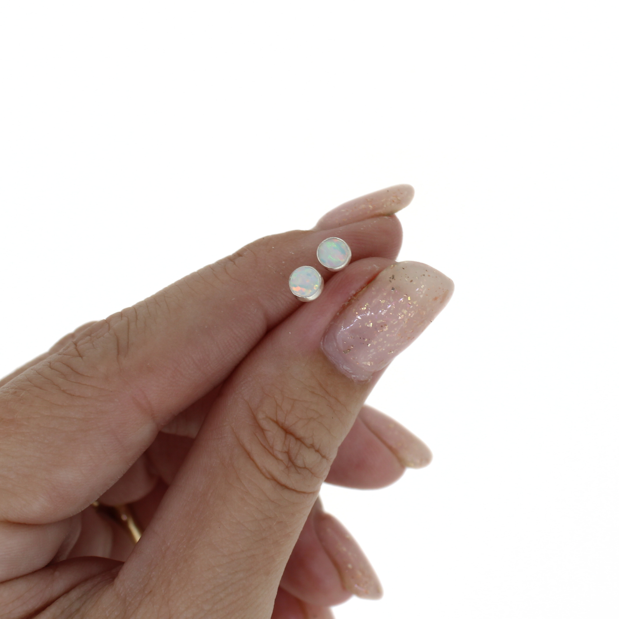 Brianne & Co. sterling silver tiny simulated opal stud earrings in hand for size reference 