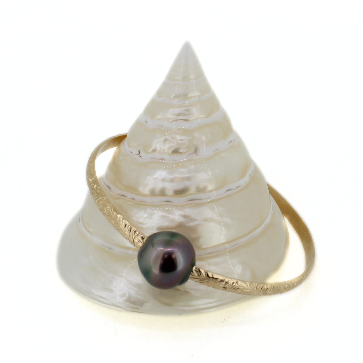 Gold floral printed bangle bracelet with genuine Tahitian pearl displayed on a white shell