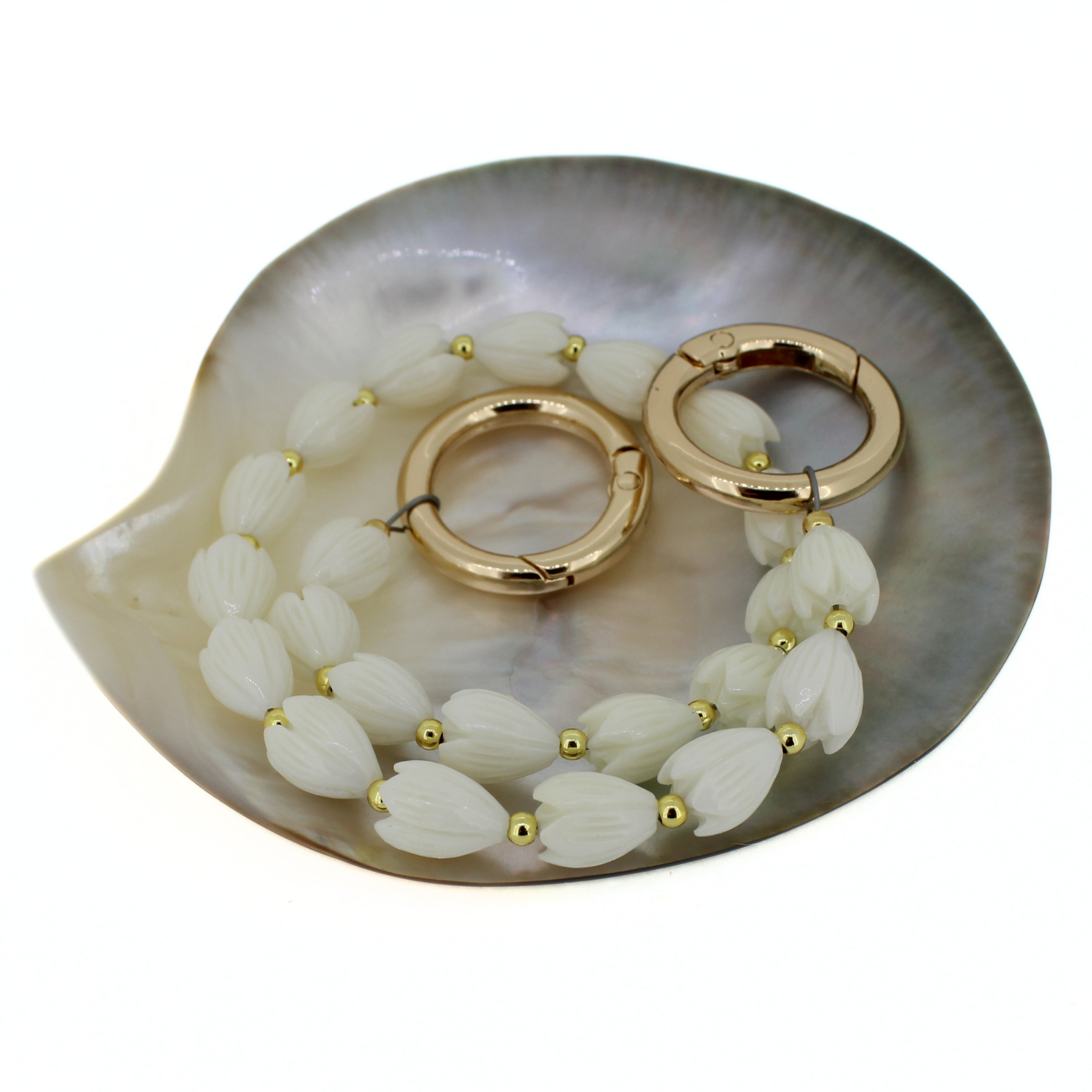Short flower purse lei on a gray shell dish: white petal beads with gold rings and accents