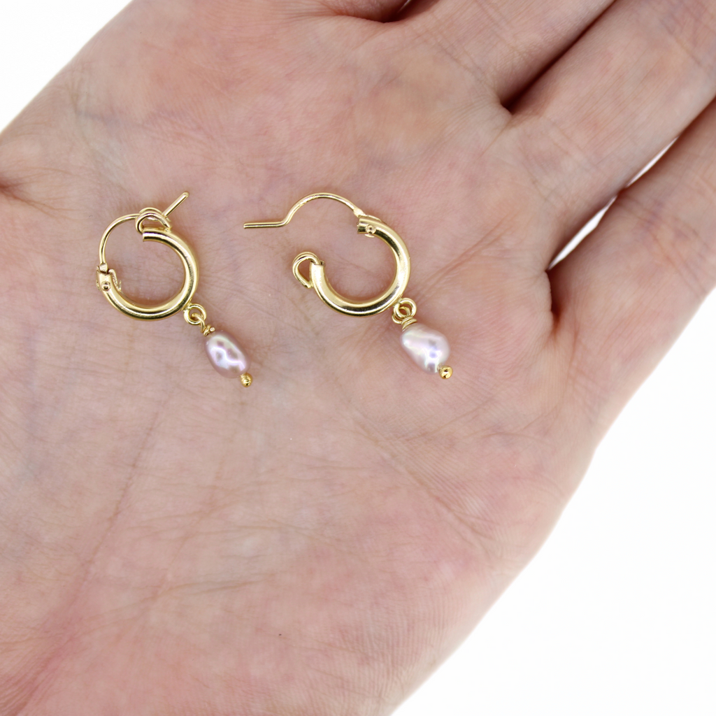 Brianne & Co huggie hoops with pink pearls in gold fill, shown in hand