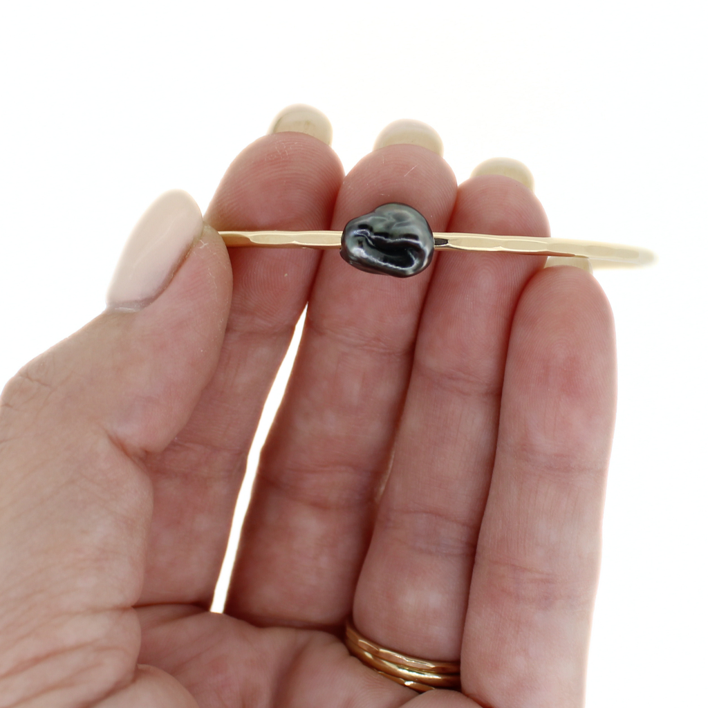 Gold fill bangle with dark grey Tahitian keshi pearl hand made by Brianne & Co. on hand for size reference