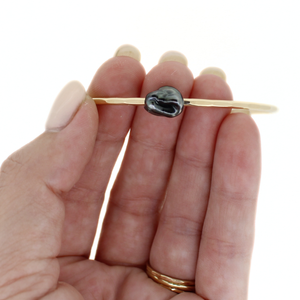 Gold fill bangle with dark grey Tahitian keshi pearl hand made by Brianne & Co. on hand for size reference