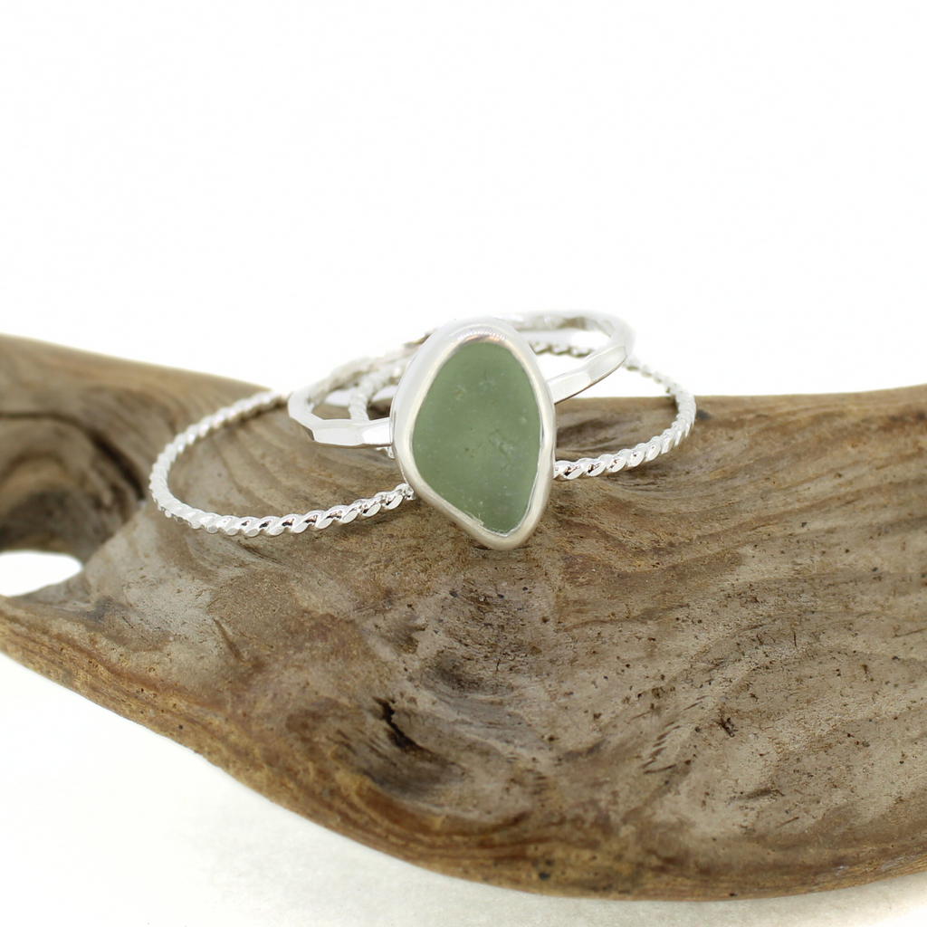 Brianne and Co. Sterling Silver Light Green Sea Glass Ring with Textured Bands Size 10 on a piece of wood