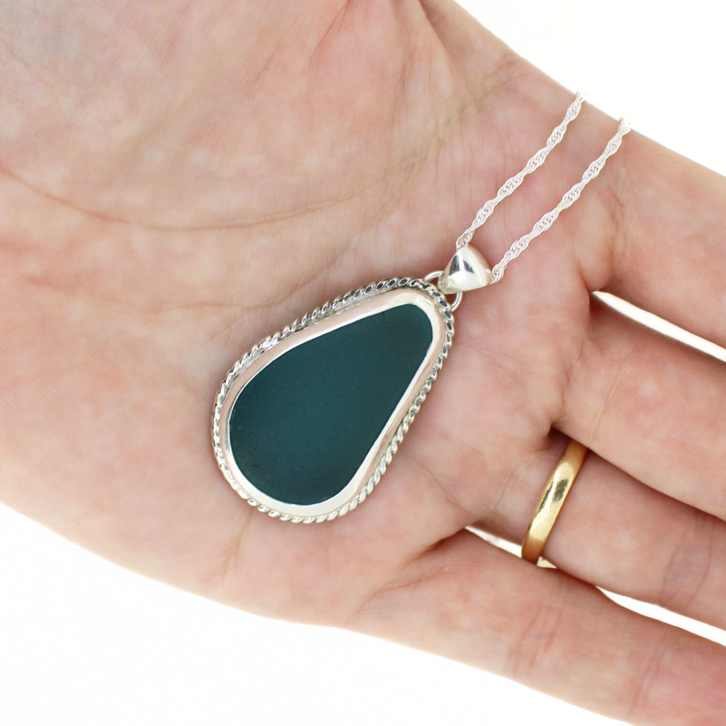 Brianne and Co  Sterling Silver Bezeled Blue Sea Glass Necklace  in a palm of a hand